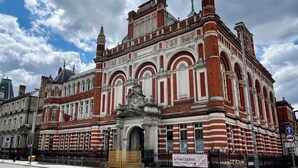 A historic building with red brick and white stone architecture, featuring a prominent archway and a statue in front. - Dodi Apartments (London)