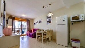 A modern apartment with a dining area, a purple sofa, a white refrigerator, and a microwave. - AMBAR 18B - Apartment with sea views very close to the beach and supermarkets (Calpe)