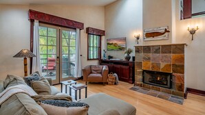 Una sala de estar acogedora con chimenea, un sofá, una silla y un comedor con mesa y sillas.