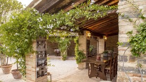 An outdoor patio area with a wooden pergola, stone walls, and potted plants. - Villa Teloni, your exclusive place w/private pool (San Severino Marche)