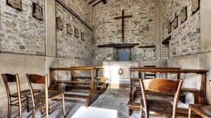 A stone-walled room with wooden benches and a central altar. - Villa Teloni, your exclusive place w/private pool (San Severino Marche)