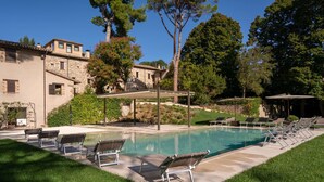 A swimming pool with lounge chairs, a pergola, and a stone building in the background. - Villa Teloni, your exclusive place w/private pool (San Severino Marche)