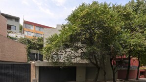 Ein Wohnhaus mit Garage, einem Baum davor und einer Backsteinmauer.
