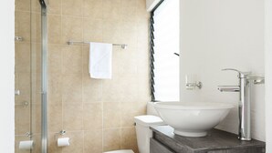 Ein modernes Badezimmer mit Duschkabine aus Glas, Toilette in Weiß und einem Waschbecken auf Holzablage.