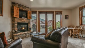 A cozy living room with a stone fireplace, leather sofa, and a dining area with wooden chairs. - Ground-Floor Unit w/Views, Close to Trails & Golf! (Keystone)