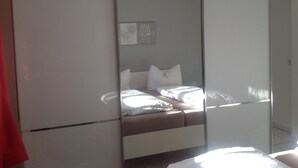 A bedroom with a bed, a wardrobe, and a mirror. - Holiday apartments in the middle of the biosphere reserve (Middelhagen)