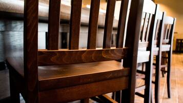 A row of wooden chairs with a slatted backrest, arranged in a dining area.