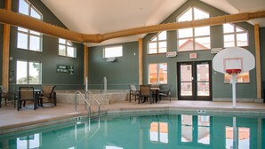 Piscina interior con aro de baloncesto, varias ventanas y zonas de estar.