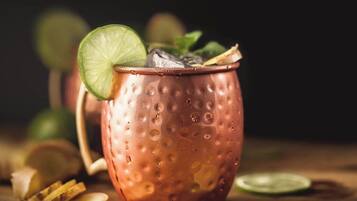 A copper mug with a lime slice and mint leaves, placed on a wooden surface with lime slices and ginger slices around it.