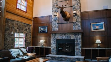 Eine Lobby mit Kamin aus Stein, Holzvertäfelung, einem aufgehängten Elchkopf und einer gemütlichen Sitzecke.