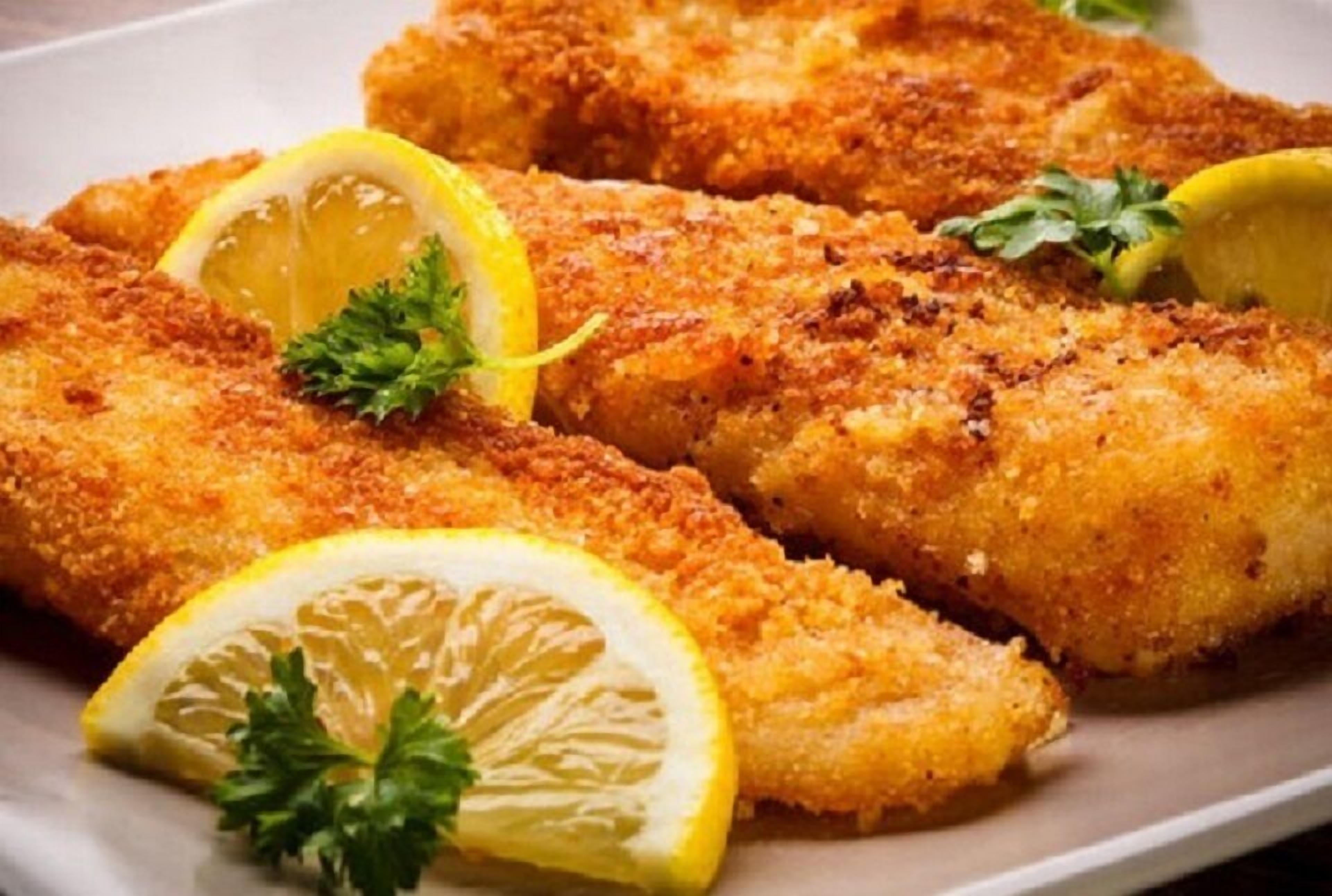 A plate of breaded and fried fish garnished with lemon and parsley.