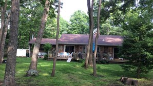 A house with a covered porch, a lawn, and trees. - Walk to private beach in Clearwater (East Hampton)