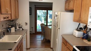 A kitchen with wooden cabinets, a refrigerator, a toaster, and a coffee maker. - Walk to private beach in Clearwater (East Hampton)