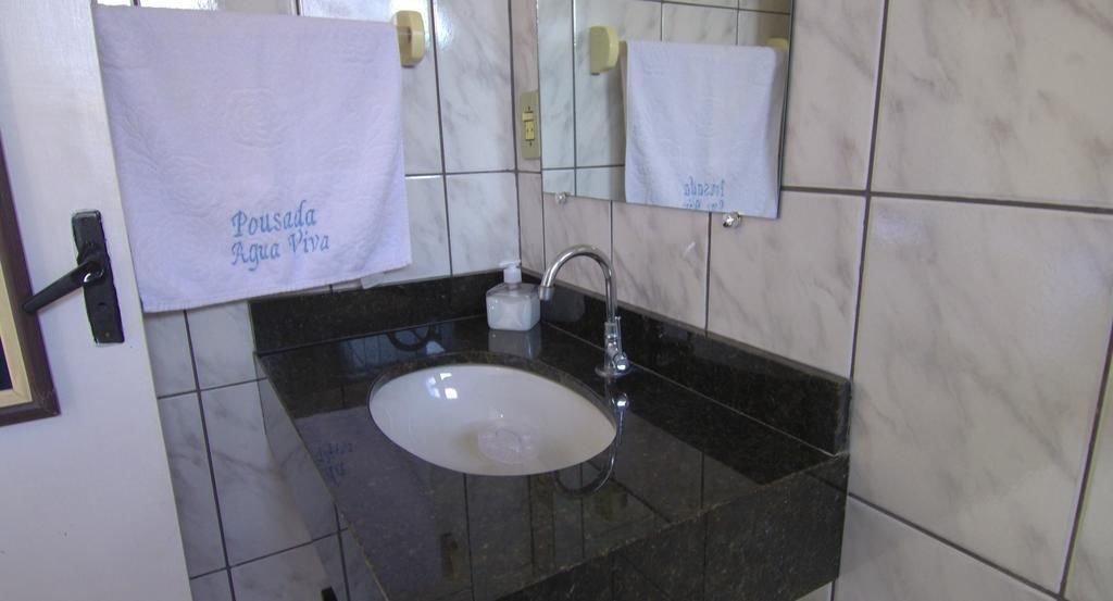 Un baño con lavamanos de mármol, un espejo y dos toallas colgadas en la pared.