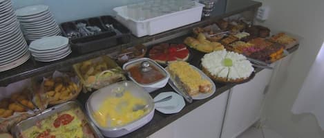 A buffet with various dishes, including a casserole, fruit, and a variety of desserts.