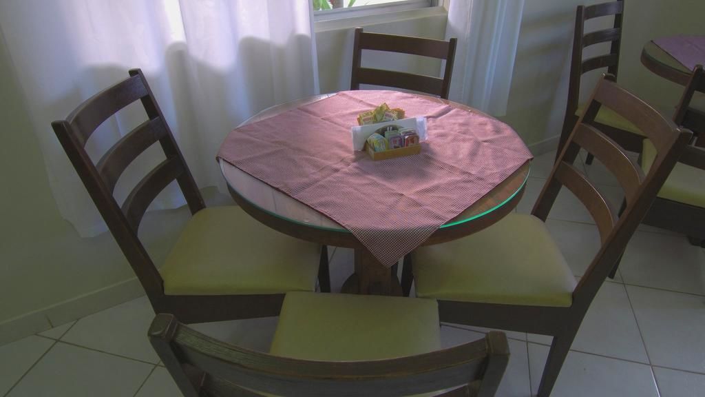 A round dining table with a glass top, surrounded by wooden chairs with cushioned seats.
