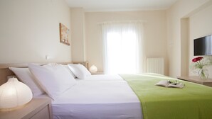 A hotel room with a bed, a nightstand, a lamp, a TV, and a window with curtains. - Villa Sonia (Anthemis villas) - Private Pool, private BBQ, playground for kids! (Kariotes)