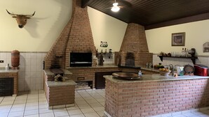 A kitchen with a brick oven, a bull head decoration, and a ceiling fan. - Come and relax in the second best climate in the world. (Atibaia)