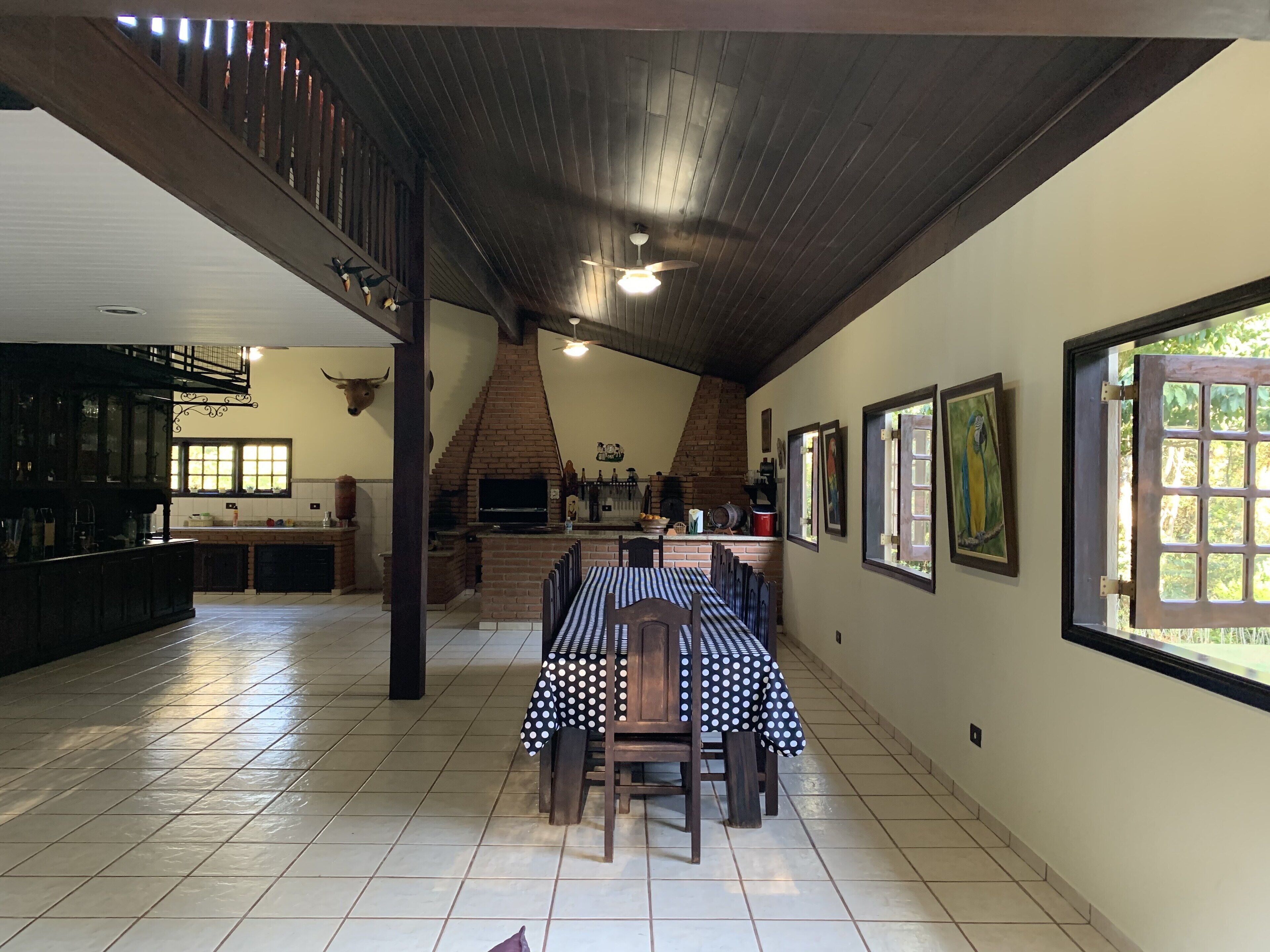 Une cuisine spacieuse dotée d’un four en briques, un coin repas avec une table pour quatre personnes et un escalier menant à l’étage supérieur.
