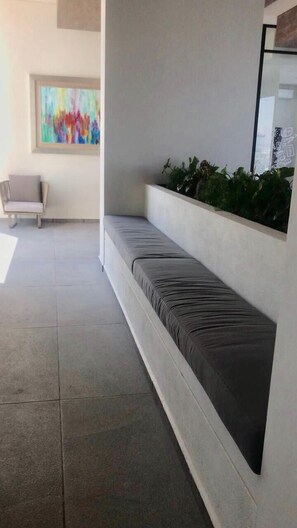 A modern waiting area with a bench, a colorful abstract painting, and a potted plant. - Nuevo Lujoso Depto Residencial Queretaro (Querétaro)