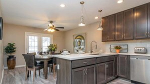 A modern kitchen with dark cabinets, a central island, and pendant lighting. - At Base of Cottonwoods! * Private Hot Tub * Xbox (Cottonwood Heights)