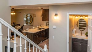 A modern kitchen with a central island, a dining area with a chandelier, and a staircase leading to an upper level. - At Base of Cottonwoods! * Private Hot Tub * Xbox (Cottonwood Heights)