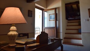 A room with a wooden table, a lamp, and a staircase leading to an upper level.