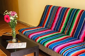 Un canapé rayé aux couleurs vives et un vase rempli de fleurs, posé sur une table.