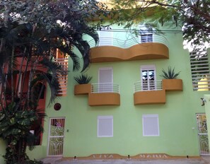 A building with a green facade, multiple balconies, and a sign reading "VIVA MARIA".