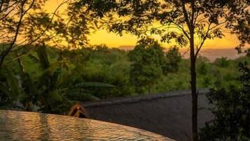 A swimming pool with a view of trees and a sunset.
