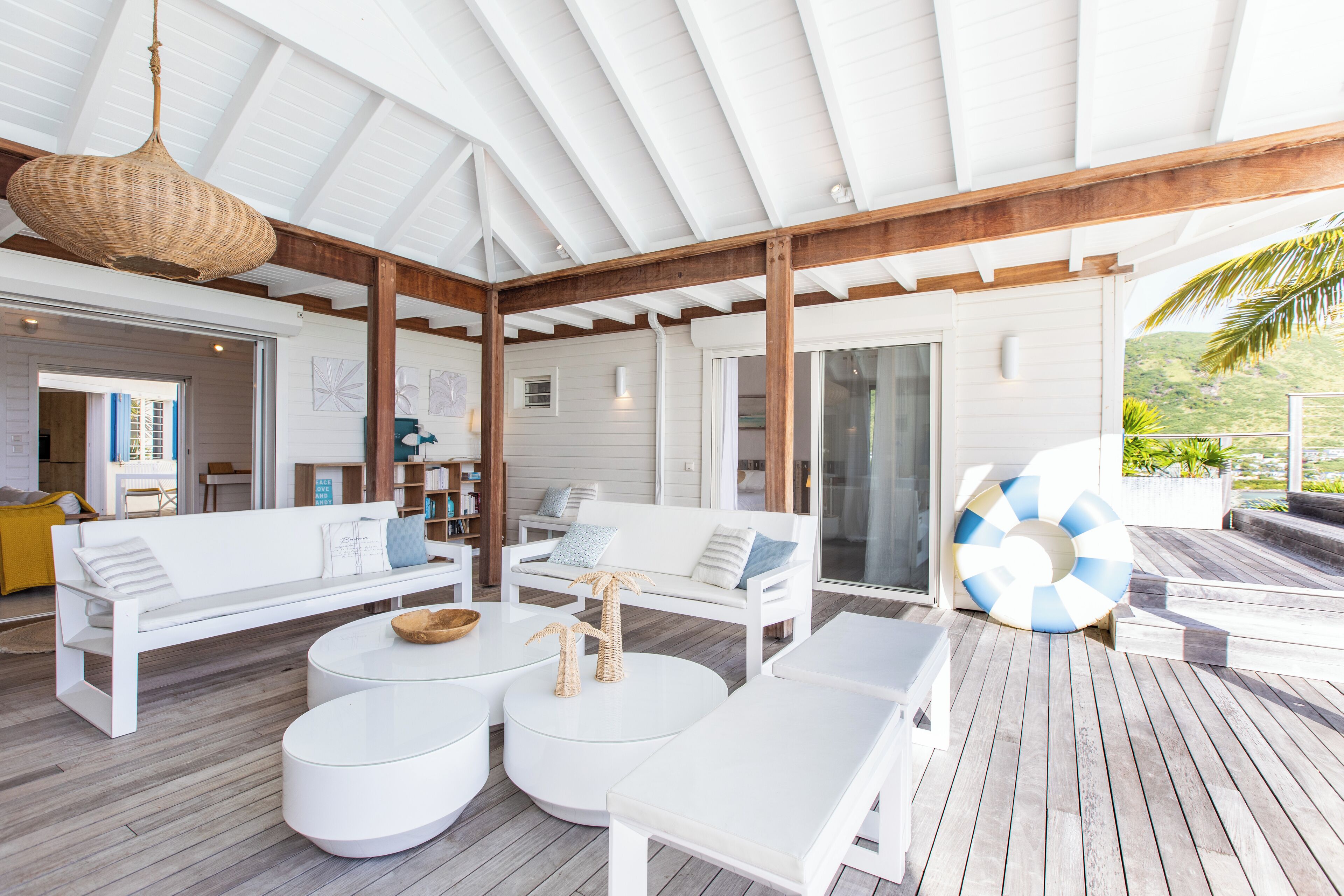 A covered outdoor seating area with white furniture, a round table, and a large umbrella.