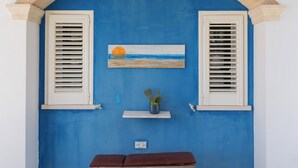 Una habitación con pared azul, un banco de madera y un cuadro de una puesta de sol.
