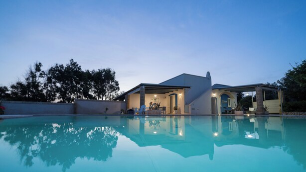 Una casa moderna con piscina, patio y zona de estar al aire libre.