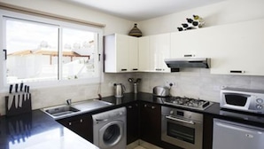 A compact kitchen with a washing machine, oven, microwave, and a sink with a knife block. - Luxury Penthouse Apartment. Free WI-FI and UK TV. Pool. Large veranda. Air Con. (Unknown)