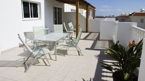 A patio with a table and chairs, a wooden pergola, and a potted plant. - Luxury Penthouse Apartment. Free WI-FI and UK TV. Pool. Large veranda. Air Con. (Unknown)