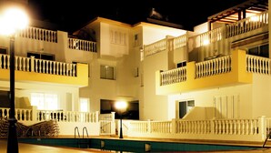 A multi-story hotel with balconies, a swimming pool, and outdoor lighting. - Luxury Penthouse Apartment. Free WI-FI and UK TV. Pool. Large veranda. Air Con. (Unknown)