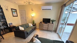A living room with a sofa, a television on a wooden cabinet, and a sliding glass door leading to an outdoor area. - Luxury Penthouse Apartment. Free WI-FI and UK TV. Pool. Large veranda. Air Con. (Unknown)