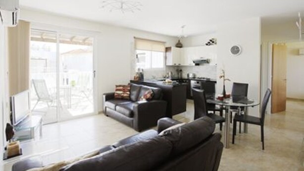 A modern living room with a sofa, a dining table, and chairs. There is a kitchen area with cabinets and a microwave. - Luxury Penthouse Apartment. Free WI-FI and UK TV. Pool. Large veranda. Air Con. (Unknown)