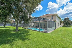 Una casa con piscina, terraza techada y césped bien cuidado.