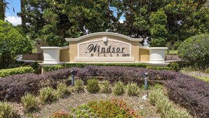 Un letrero ajardinado con el texto 'Windsor Hills 2600' rodeado de plantas y arbustos.