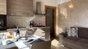 Una cocina moderna con comedor, sofá y una lámpara fijada a la pared.