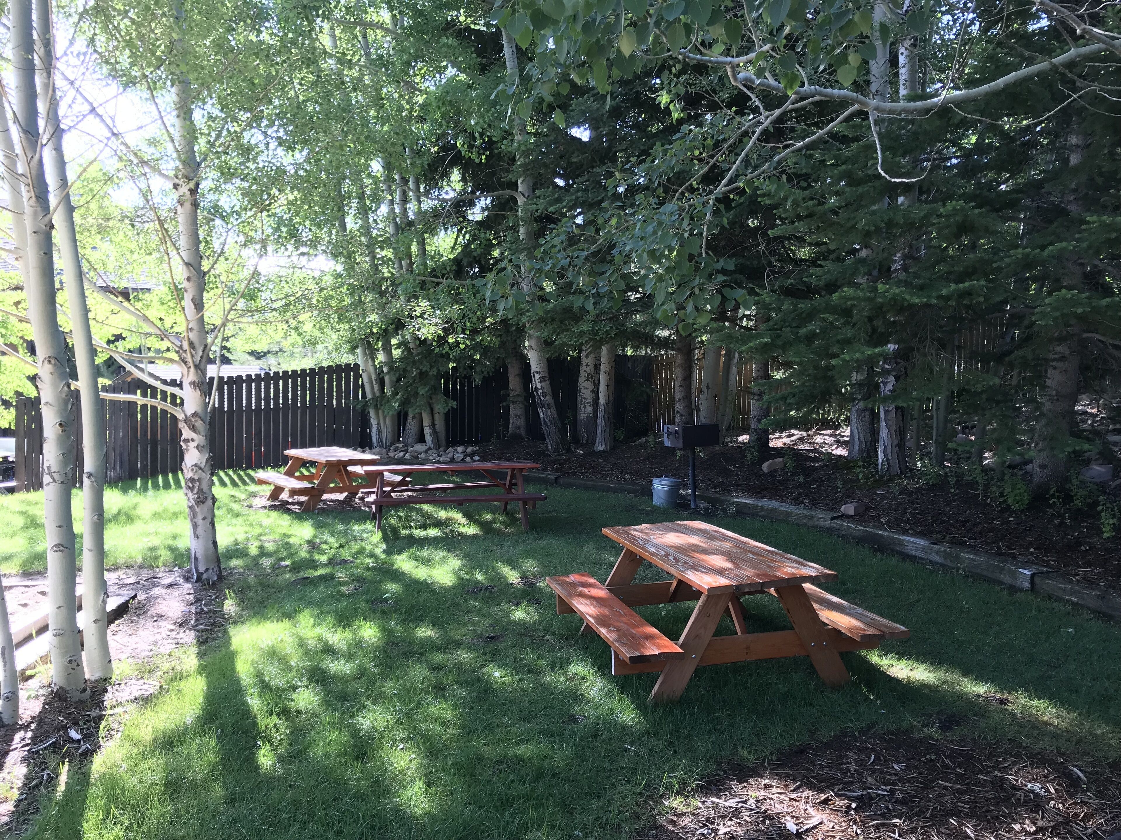 Un jardin avec une table de pique-nique en bois et une boîte aux lettres.
