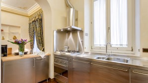Una cocina moderna con electrodomésticos de acero inoxidable, un lavamanos doble y una ventana con cortinas.