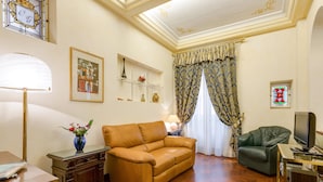 Una sala de estar con un sofá, televisor, lámpara y un jarrón decorativo.