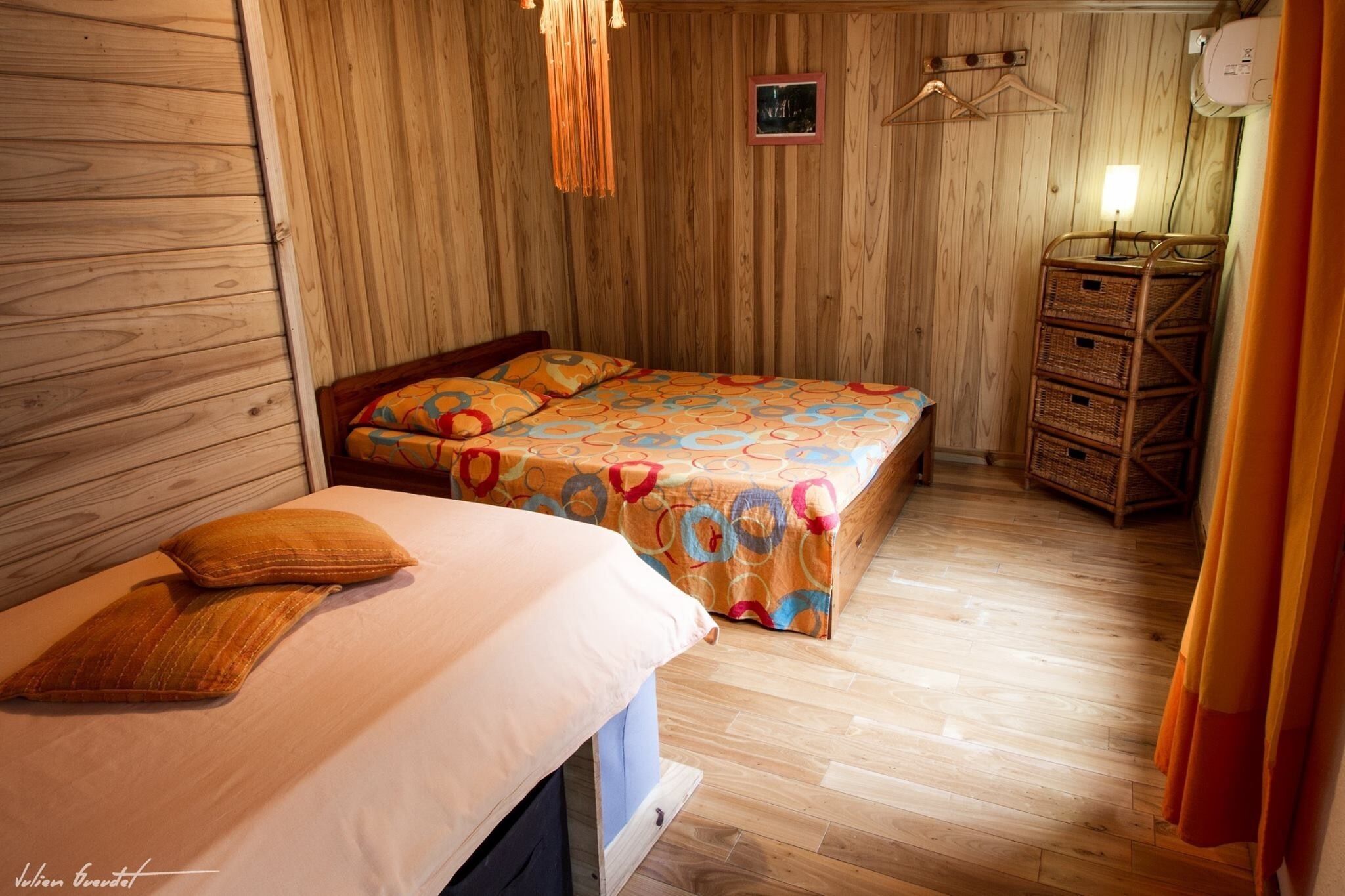 A wooden-paneled room with a bed, a dresser, and a hanging light fixture.