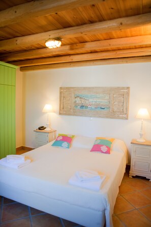 Ein Schlafzimmer mit Holzboden, einem Bett mit weißer Bettwäsche, zwei Nachttischen mit Lampen und einem Bild an der Wand.