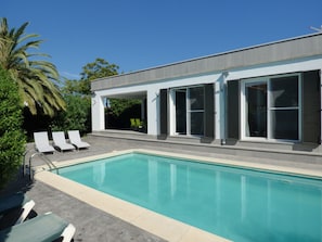 A modern house with a swimming pool, outdoor seating, and large windows.