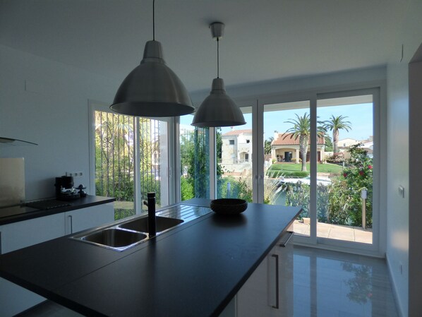 A modern kitchen with a large window, a black countertop, and two pendant lights.