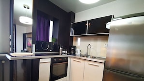 A modern kitchen with a built-in oven, a stainless steel refrigerator, and a dark-colored countertop. - Studio G by MRG Apartments | Steps away from Metro & Amenities (București)