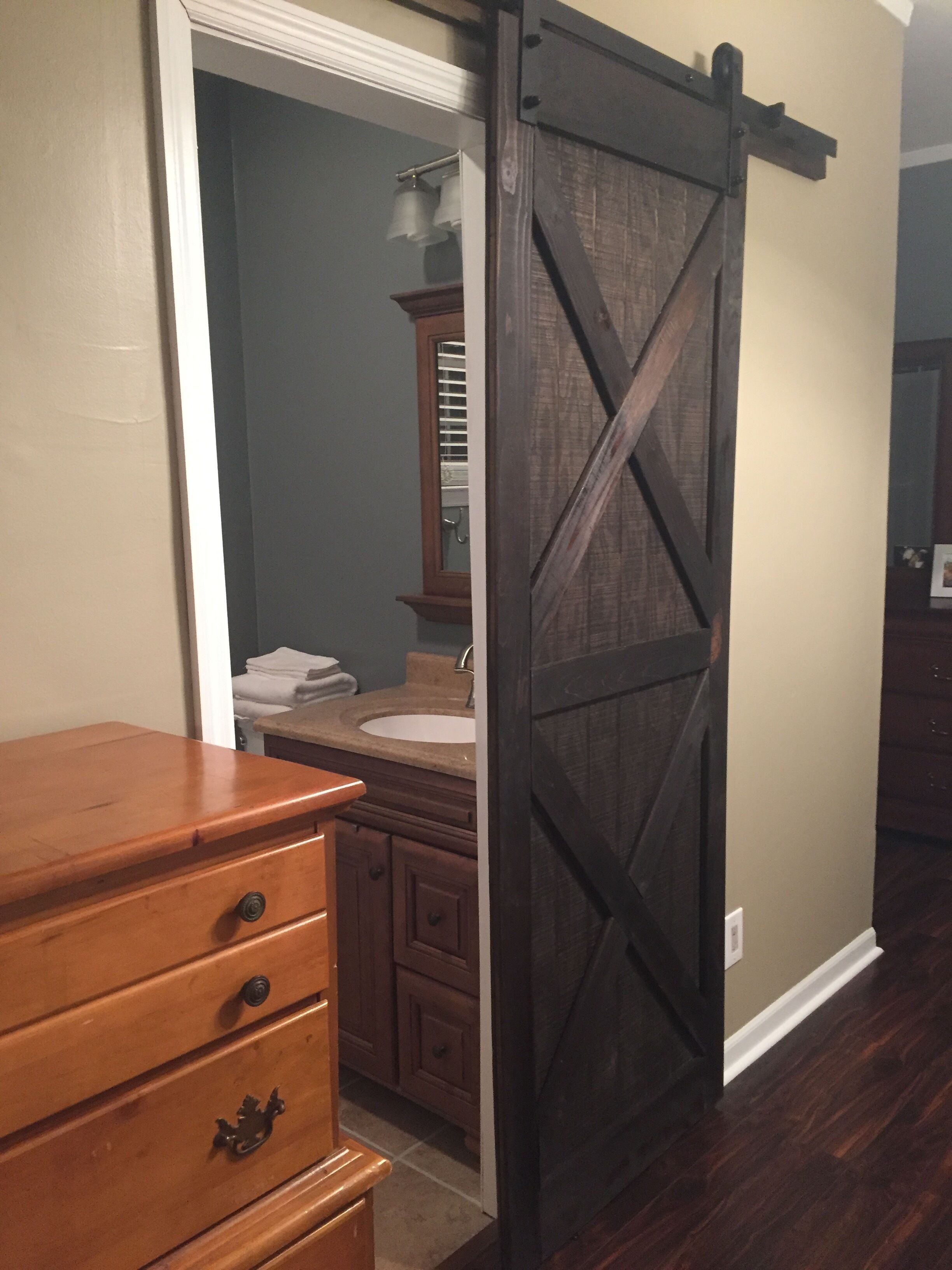 A bathroom with a wooden dresser, a sink, and a dark wooden sliding door.